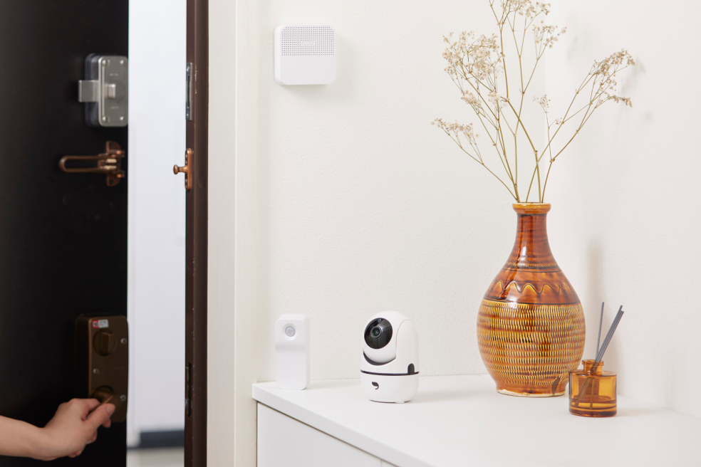 防犯ブザーと防犯センサー、防犯カメラを設置した玄関を出入りする女性の画像